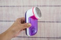 Female hand holds a machine to remove pellets from clothes. Wooden background