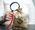 Female hand holds magnifying glass over money bag and up arrow. Concept analysis of profits and budget in the company. Successful Royalty Free Stock Photo