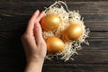 Female hand holds nest with golden eggs on background, top view Royalty Free Stock Photo