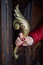 Female hand holds ornate brass door handle Royalty Free Stock Photo