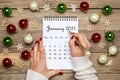 Female hand holds pen, open Calendar January 2021, Christmas decor on wooden table Royalty Free Stock Photo