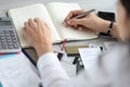 Female hand holds pen over diary near bank cards and calculator. Royalty Free Stock Photo