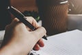 Female hand holds a pen and writes in a notebook, dark background Royalty Free Stock Photo