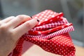 Female hand holds a pile of five types of red and white cotton fabrics with different prints: checkered, striped, circle, star