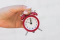 Female hand holds a red alarm clock on the outstretched hand against the background of a white brick wall Royalty Free Stock Photo