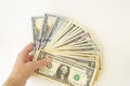 A female hand holds several hundred dollar bills spread out in a fan on a white background Royalty Free Stock Photo