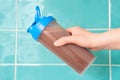 Female hand holds shaker with protein shake against background of mint tiles. Royalty Free Stock Photo