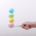 Female hand holds a spoon on which multi-colored eggs are balanced, on a white background. Unusual design, Easter concept, copy