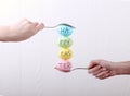 Female hand holds a spoon on which multi-colored eggs are balanced, on a white background. Unusual design, Easter concept, copy