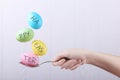 Female hand holds a spoon on which multi-colored eggs are balanced, on a white background. Unusual design, Easter concept, copy