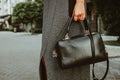 Female hand holds a square leather bag. Street look of a business woman. An independent strong business lady left the office