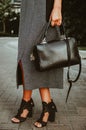 Female hand holds a square leather bag. Street look of a business woman. An independent strong business lady left the office