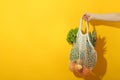 Female hand holds string bag with food on yellow background Royalty Free Stock Photo