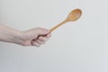 Female hand holds up a big wooden spoon on a white background. Raised up clenched fist for protest. Put the power back in your Royalty Free Stock Photo