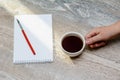 Female hand holds a white cup of coffee stands on the table. Notepad and fountain pen Royalty Free Stock Photo