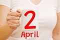 A female hand holds a white mug with inscription April 2. Business concept Royalty Free Stock Photo