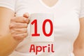 A female hand holds a white mug with inscription April 10. Business concept Royalty Free Stock Photo