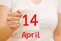 A female hand holds a white mug with inscription April 14. Business concept Royalty Free Stock Photo