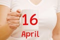 A female hand holds a white mug with inscription April 16. Business concept Royalty Free Stock Photo