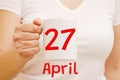 A female hand holds a white mug with inscription April 27. Business concept Royalty Free Stock Photo