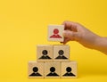 Female hand holds a wooden block on a blue background. Recruitment concept, teamwork, effective management. CEO search