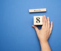 Female hand holds wooden calendar with date of eighth march