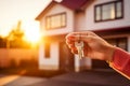 Female hand with house keys outdoors on background of cottage in sunlight. Concept of mortgage, investment, rent, real