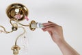 Female hand inserts a light bulb into the threaded socket. Installation of household LED lamps of corn type, in the lamp holder,