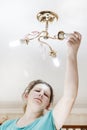 female hand inserts a light bulb into the threaded socket. she is shining. Installation of household LED lamps of corn type, in Royalty Free Stock Photo