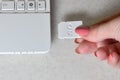 A female hand inserts a white compact SD card into the corresponding input in the side of the white netbook. Woman uses modern te