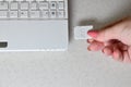A female hand inserts a white compact SD card into the corresponding input in the side of the white netbook. Woman uses modern te
