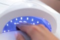 Female hand inside drying UV light machine in nail salon