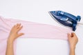 Female hand ironing clothes top view isolated on white background. Young woman with iron ironing man`s shirt seen from above Royalty Free Stock Photo