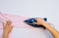 Female hand ironing clothes top view isolated on white background. Young woman with iron ironing man`s shirt seen from above Royalty Free Stock Photo