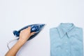 Female hand ironing clothes top view isolated on white background. Young woman with iron ironing man`s shirt seen from above Royalty Free Stock Photo