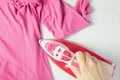 Female hand ironing pink clothes, top view. Young woman with iron ironing a shirt seen from above during housework. Royalty Free Stock Photo