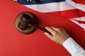 Female hand judge holds gavel on red background with american flag
