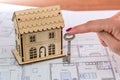 Female hand with key and wooden house model on plan Royalty Free Stock Photo