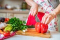 Female hand with knife cuts bell pepper in kitchen. Cooking vegetables Royalty Free Stock Photo