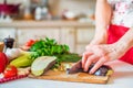 Female hand with knife cuts eggplant on board in kitchen. Cooking vegetables Royalty Free Stock Photo