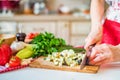 Female hand with knife cuts eggplant on board in kitchen. Cooking vegetables Royalty Free Stock Photo