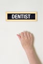 Female hand is knocking on Dentist door Royalty Free Stock Photo