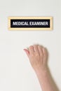 Female hand is knocking on medical examiner door Royalty Free Stock Photo