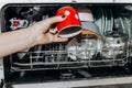 Female hand lays the dishes in an open dishwasher close-up clogged with clean, washed dishes. dry cutlery closeup. spoons forks. Royalty Free Stock Photo