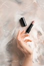 Female hand and light lipstick on table