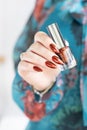 Female hand with long nails and golden maroon, manicure holds a bottle of nail polish Royalty Free Stock Photo