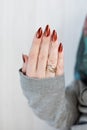 Female hand with long nails and golden maroon, manicure holds a bottle of nail polish Royalty Free Stock Photo