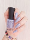 Female hand with long nails holds a bottle nail polish Royalty Free Stock Photo