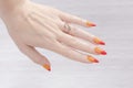 Female hand with long nails and yellow, orange and red manicure holds a bottle of nail polish Royalty Free Stock Photo