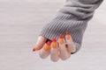 Female hand with long nails and yellow, orange and red manicure holds a bottle of nail polish Royalty Free Stock Photo